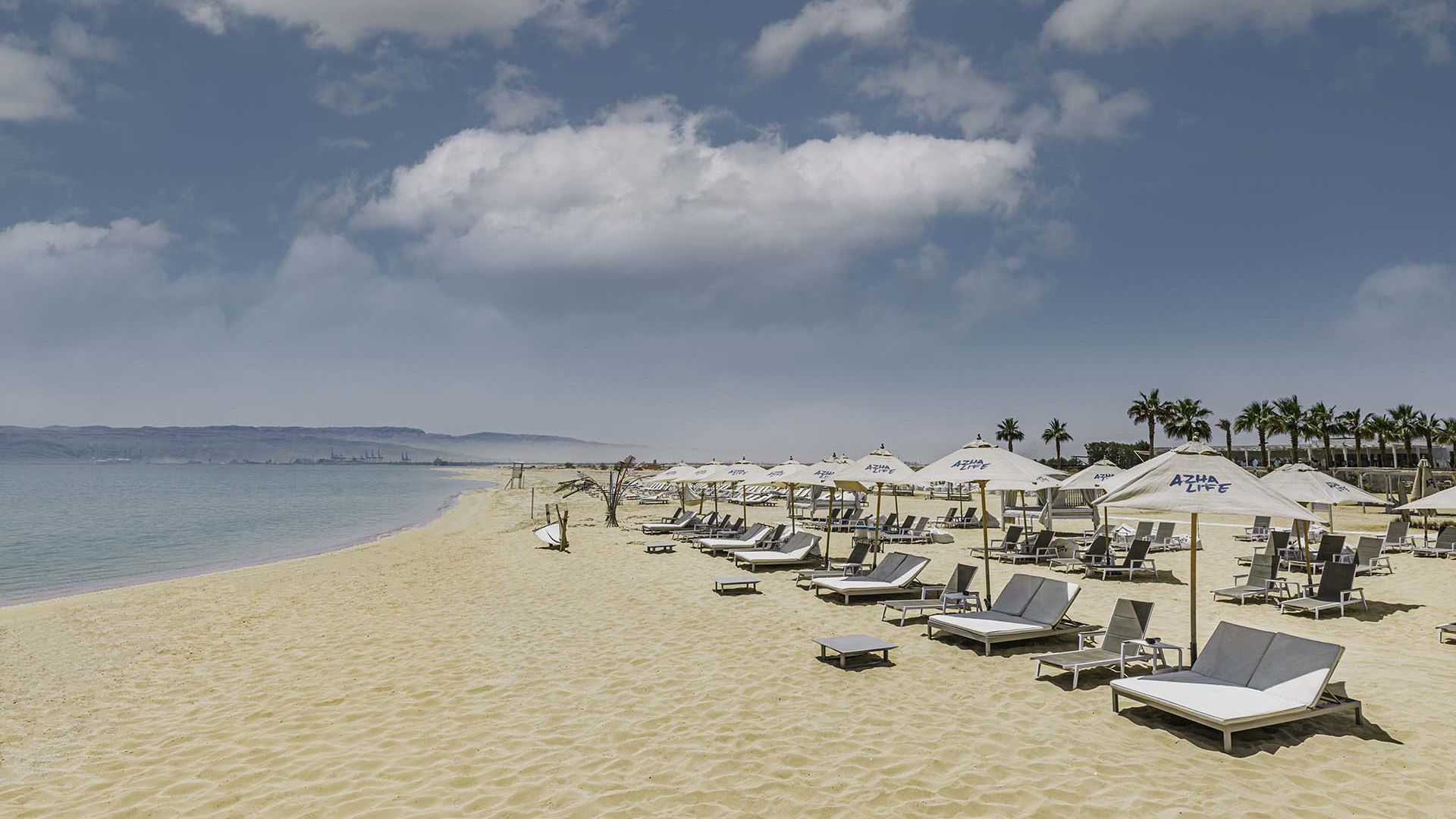 A Beach With Lounge Chairs And Umbrellas